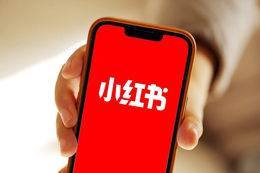 Hand holding a phone with the Xiaohongshu (Red Note) app open — Red Note marketplace